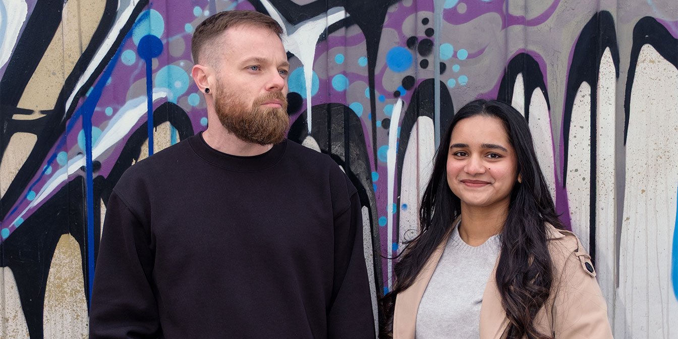 Founders of idearium, an affordable web design and SEO services agency, standing in front of a graffiti wall.